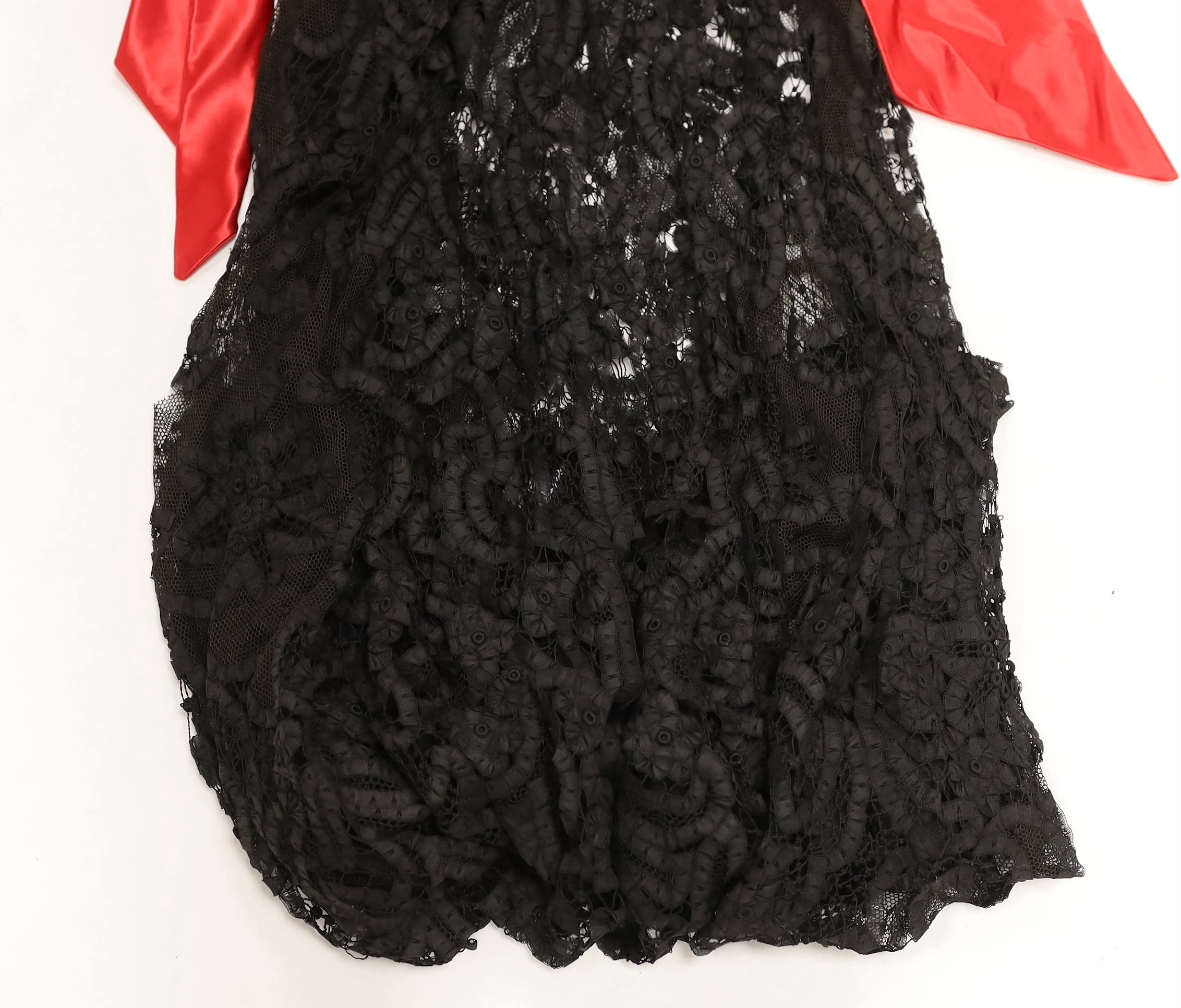 A velvet bolero with ornate polychrome silk embroidered and beaded panels, together with a full length black tape lace evening skirt (some damage) with red satin waisted sash